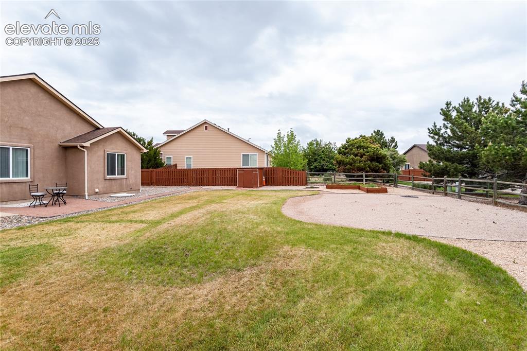 Image 43 of 49: Large yard has privacy fencing to the sides and plenty of trees to the back