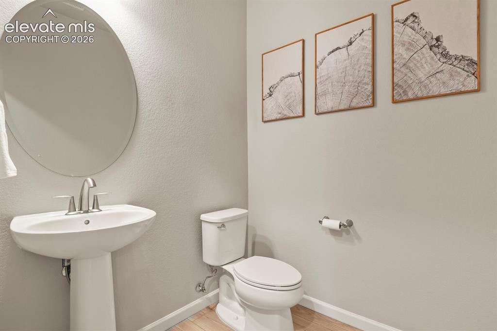 Image 11 of 29: Pedestal sink with a brushed nickel faucet, large oval mirror, and light-to
