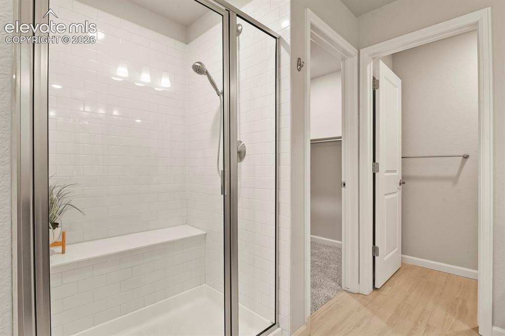 Image 19 of 29: Glass-enclosed shower with subway tile surround, built-in bench, and brushe