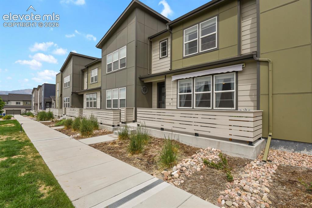 Image 2 of 29: Modern townhome exterior featuring multi-toned siding, a concrete walkway, 