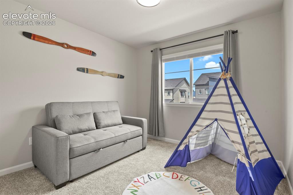 Image 22 of 29: Carpeted room featuring a double window with gray curtains and a ceiling-mo