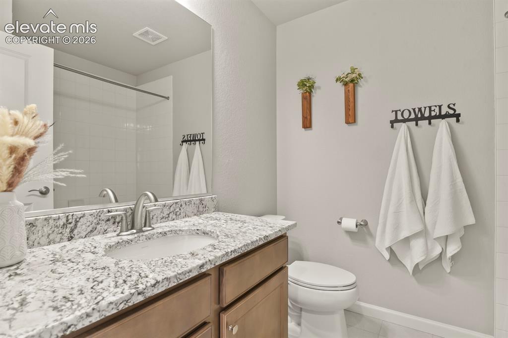 Image 24 of 29: Bathroom featuring a vanity with a light-toned, speckled countertop, an und