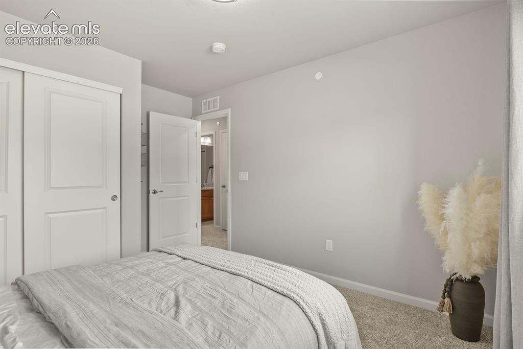 Image 26 of 29: Carpeted room with a closet featuring bi-fold doors and a standard door lea