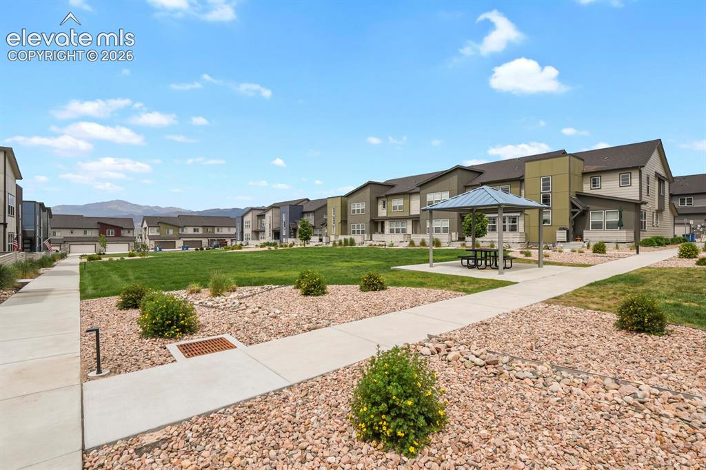 Image 28 of 29: Community green space featuring a covered gazebo with picnic table, manicur
