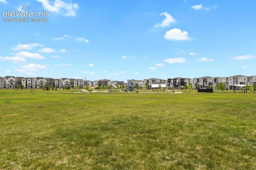Image 29 of 29: Expansive grassy field bordered by a residential development featuring vari
