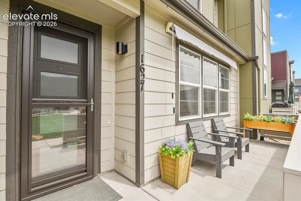 Image 3 of 29: Inviting front patio featuring light-colored siding and dark trim accents