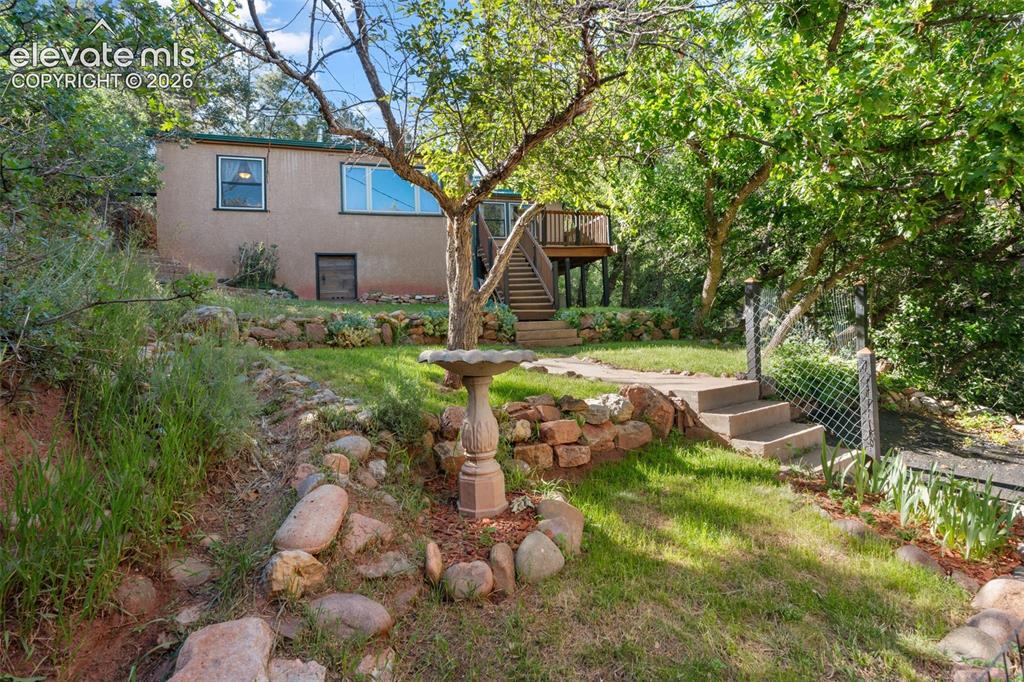 Image 1 of 40: Terraced yard featuring a stone retaining wall, concrete steps, and lush gr