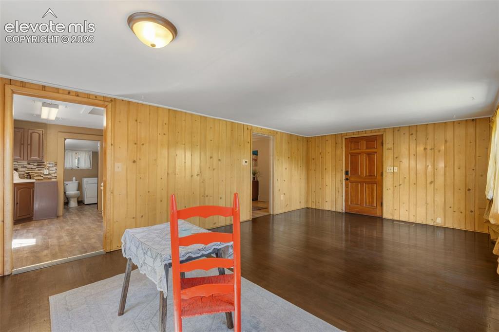 Image 11 of 40: Spacious room featuring wood-panel walls and dark wood-finish flooring