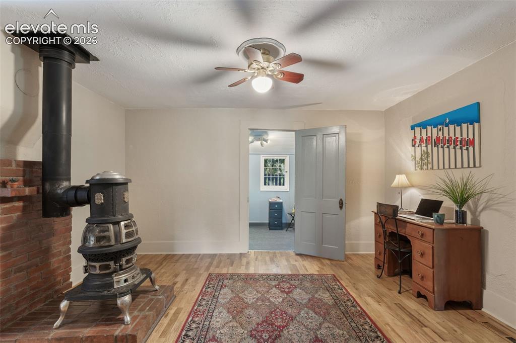 Image 12 of 40: Cast iron wood-burning stove with a brick hearth and wood-finish flooring