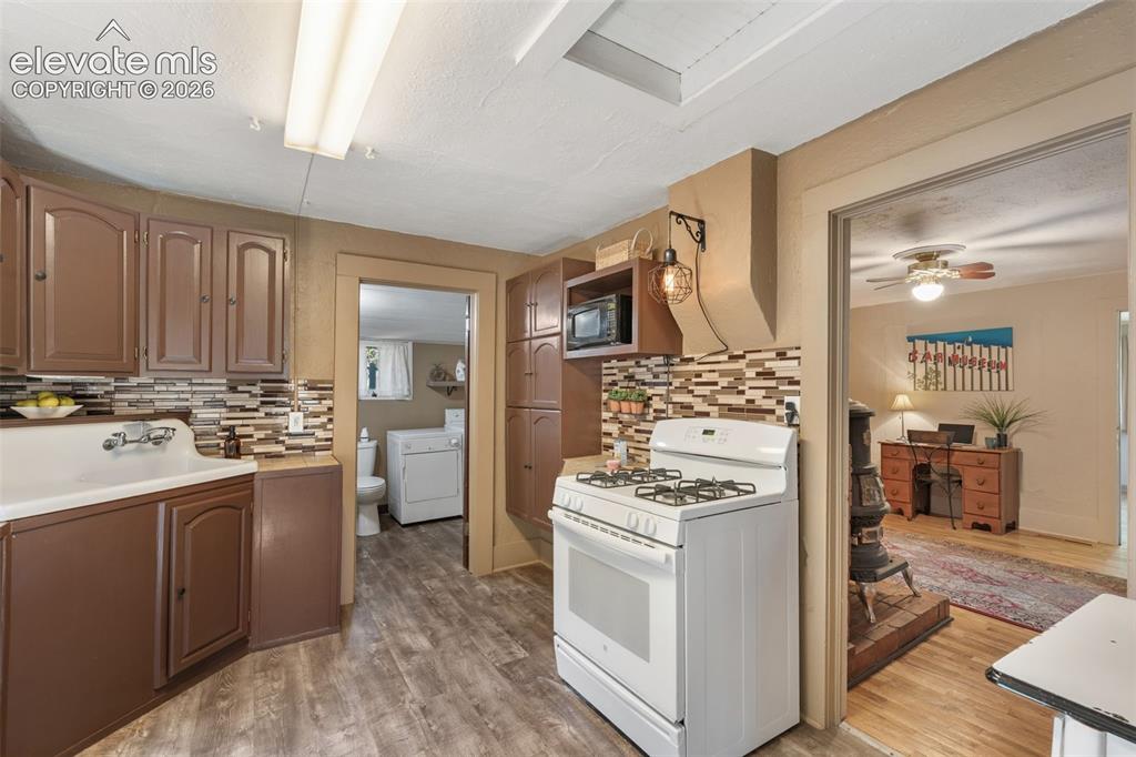 Image 17 of 40: Kitchen featuring wood-finish flooring, brown cabinetry, and a multi-toned