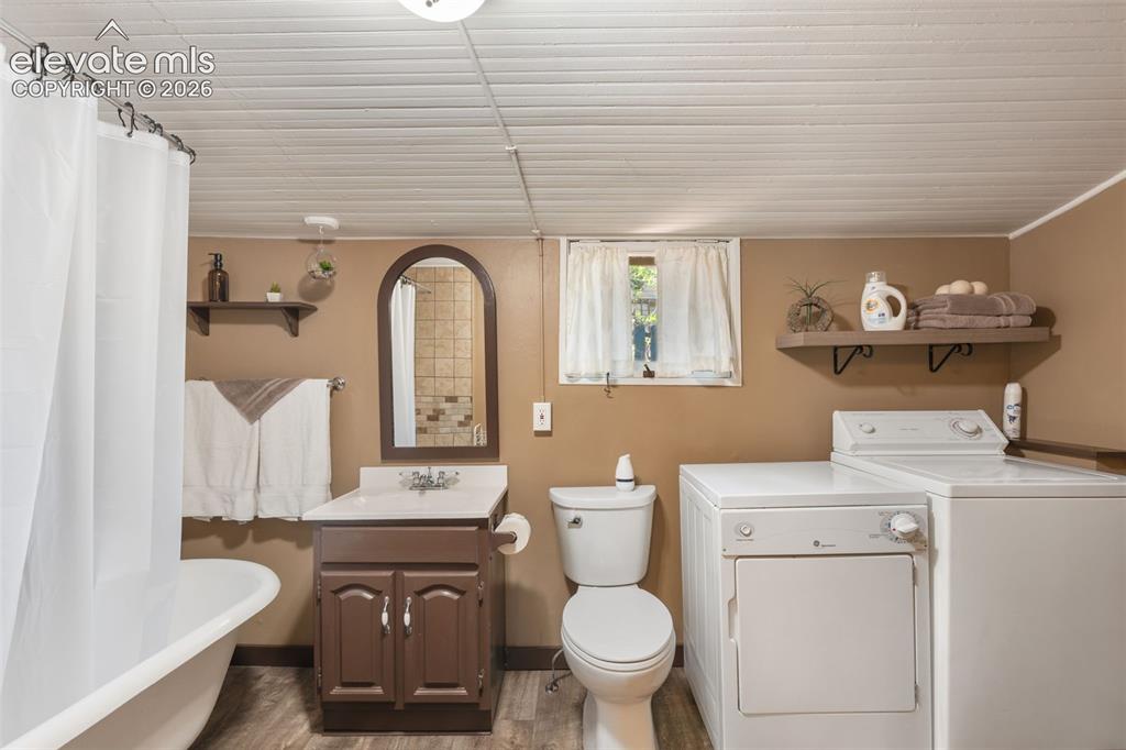Image 19 of 40: Full bathroom featuring a freestanding tub with shower, wood-finish floorin
