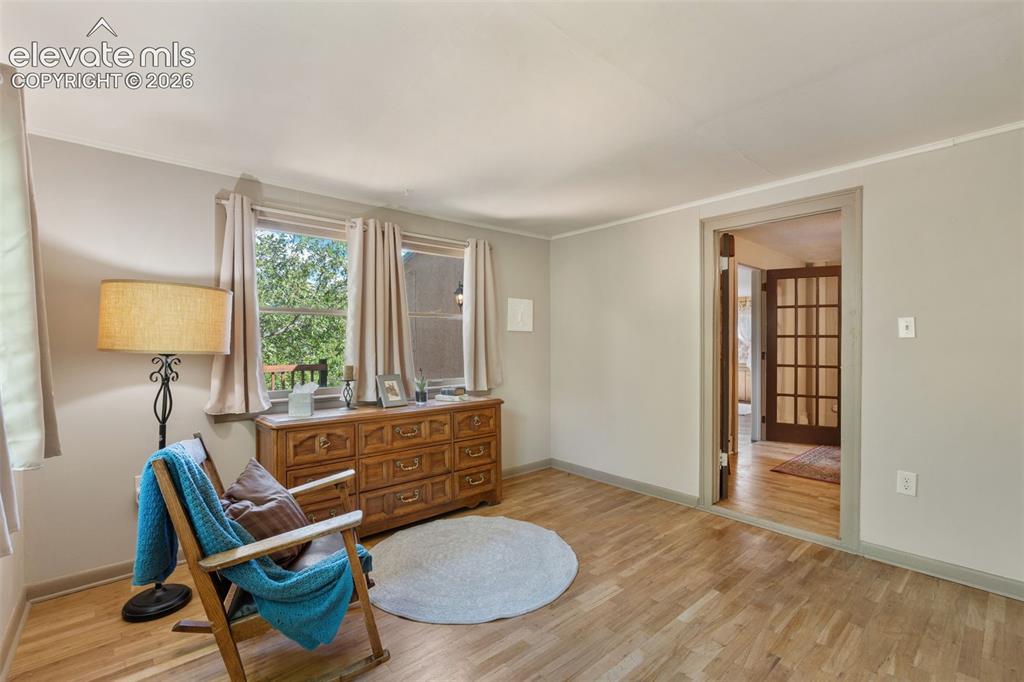 Image 24 of 40: Light wood-finish flooring extends through this room featuring two windows
