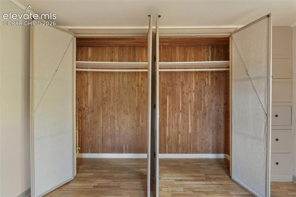 Image 26 of 40: Dual bi-fold closet doors open to reveal a cedar-lined interior with upper