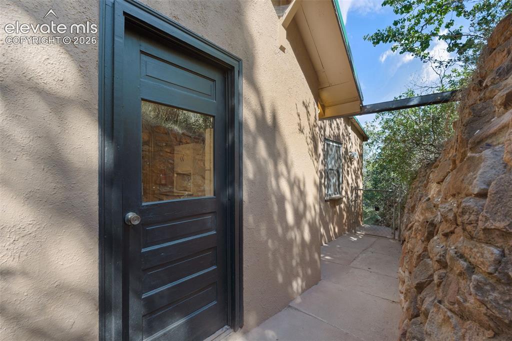 Image 30 of 40: Terracotta stucco exterior featuring a dark paneled door with glass insert,