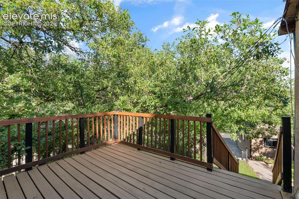 Image 31 of 40: Spacious outdoor deck with composite decking and wood railing, surrounded b
