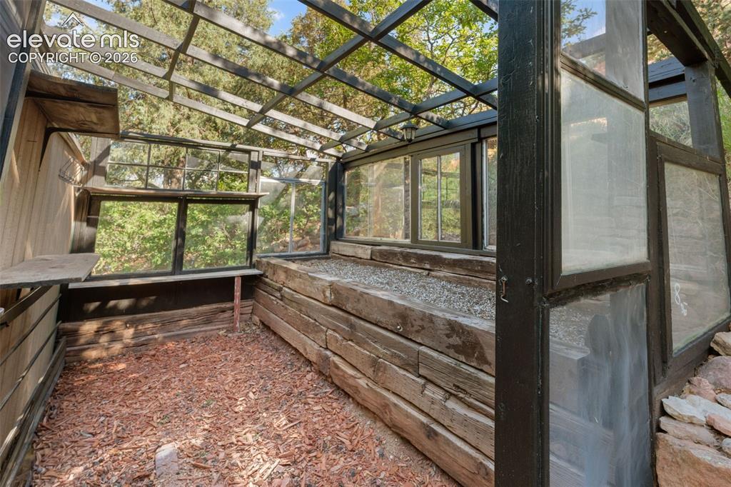 Image 34 of 40: Enclosed greenhouse structure featuring a slatted roof, multiple window pan