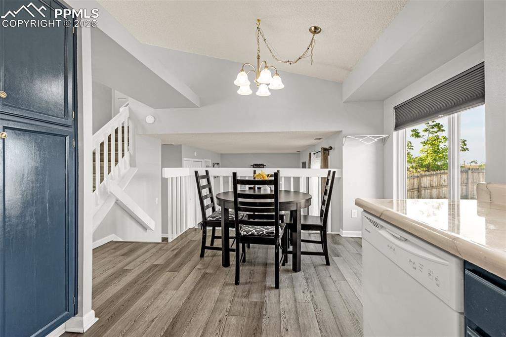 Image 10 of 30: Dining space featuring vaulted ceiling, light wood finished floors, a chand