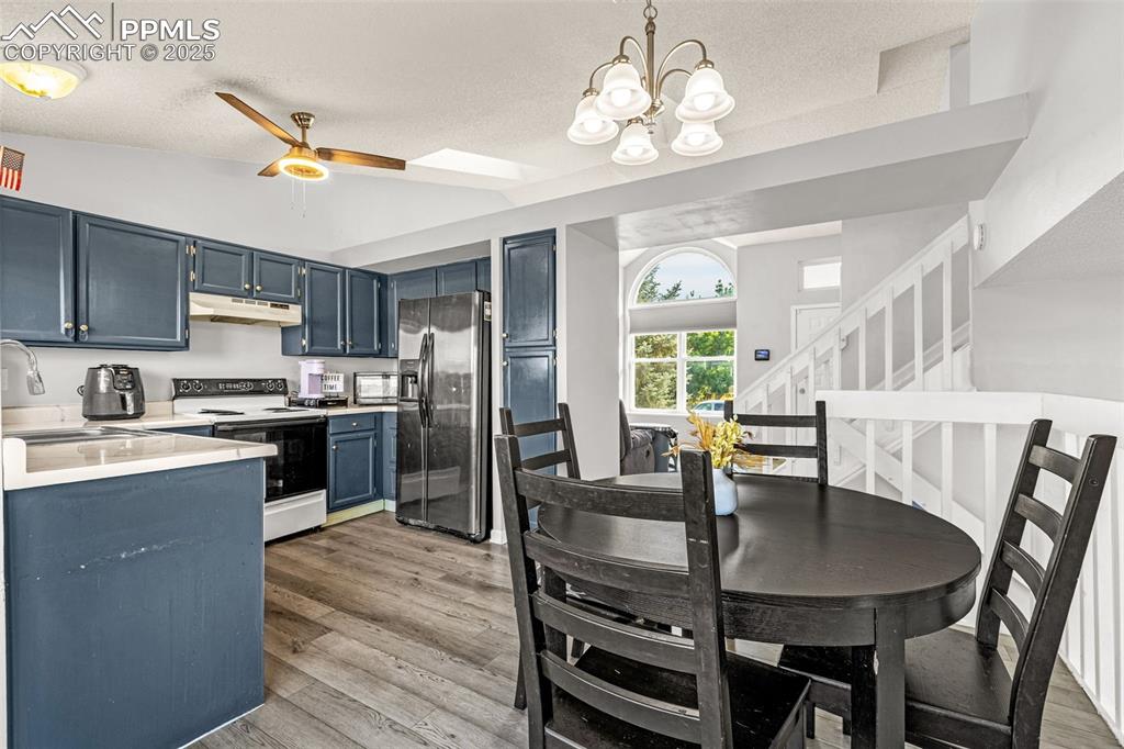 Image 7 of 30: Kitchen with light countertops, stainless steel fridge, white electric rang