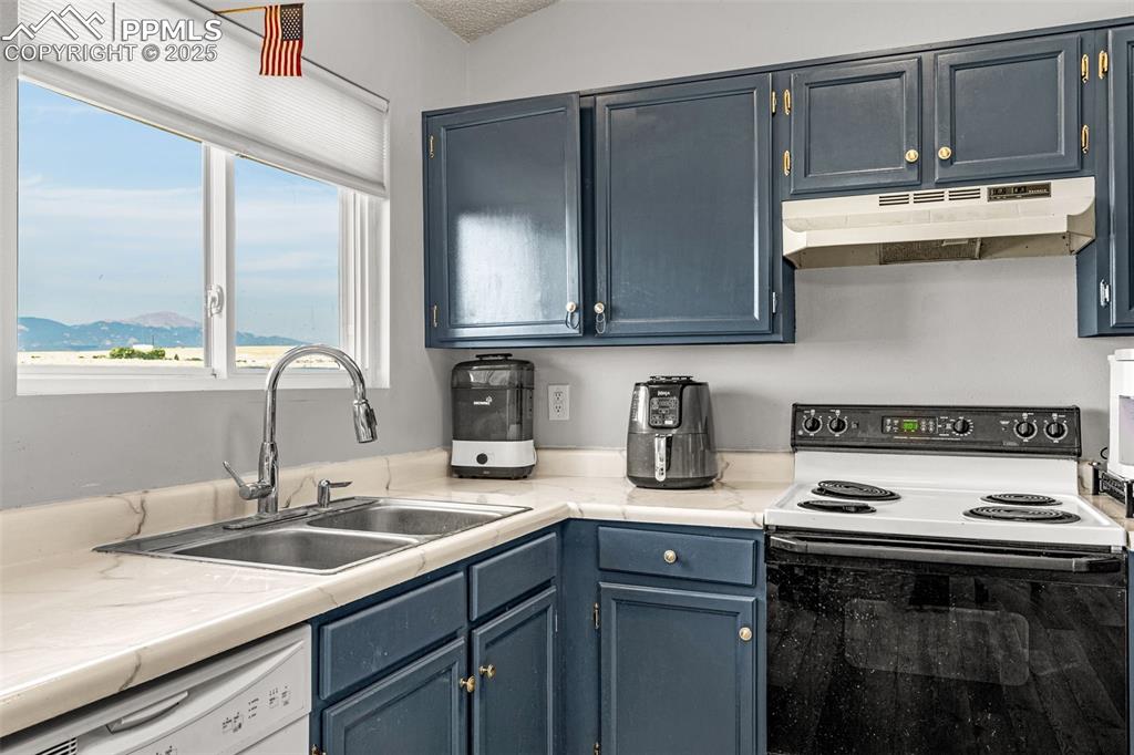Image 9 of 30: Kitchen featuring white appliances, blue cabinets, light countertops, and u
