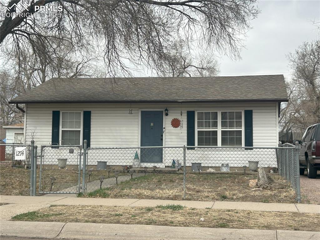 Image 3 of 16: View of front facade with a fenced front yard, a gate, and a shingled roof