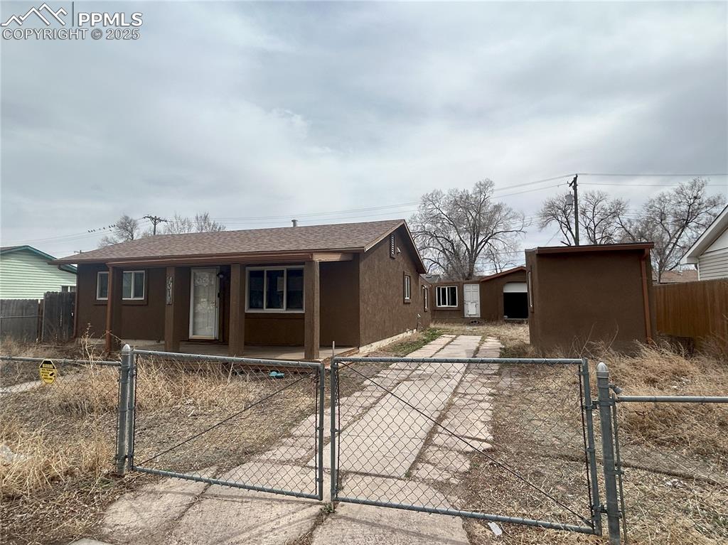 Image 6 of 16: Ranch-style house with a gate, a fenced front yard, and stucco siding