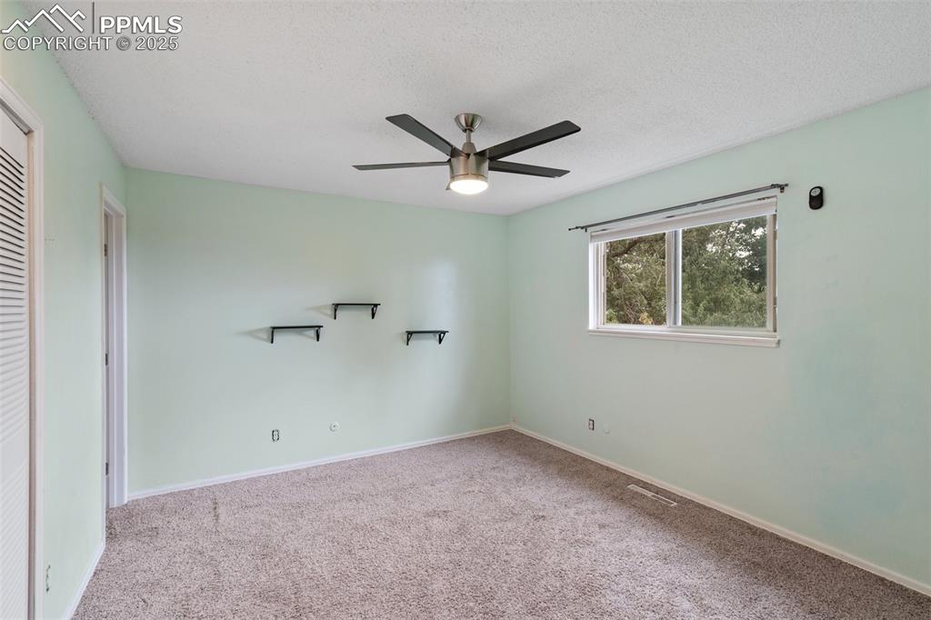 Image 10 of 25: Primary bedroom featuring light carpet, a closet, a ceiling fan, a connecte