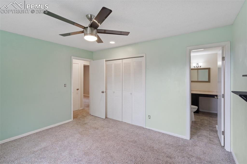 Image 11 of 25: Primary bedroom featuring light carpet, a closet, a ceiling fan, a connecte