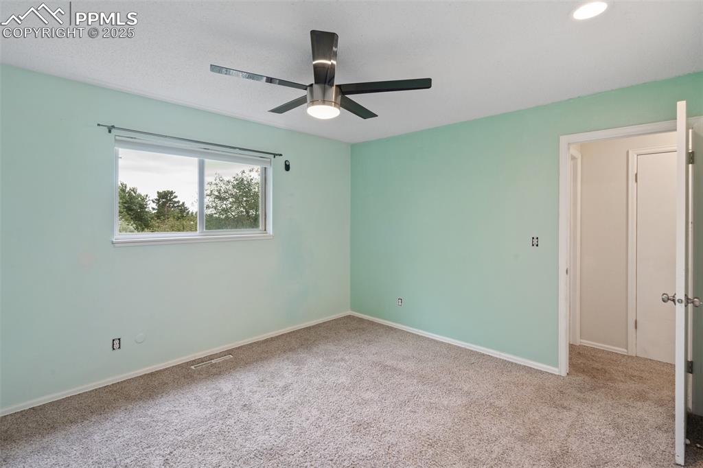 Image 12 of 25: Primary bedroom featuring light carpet, a closet, a ceiling fan, a connecte