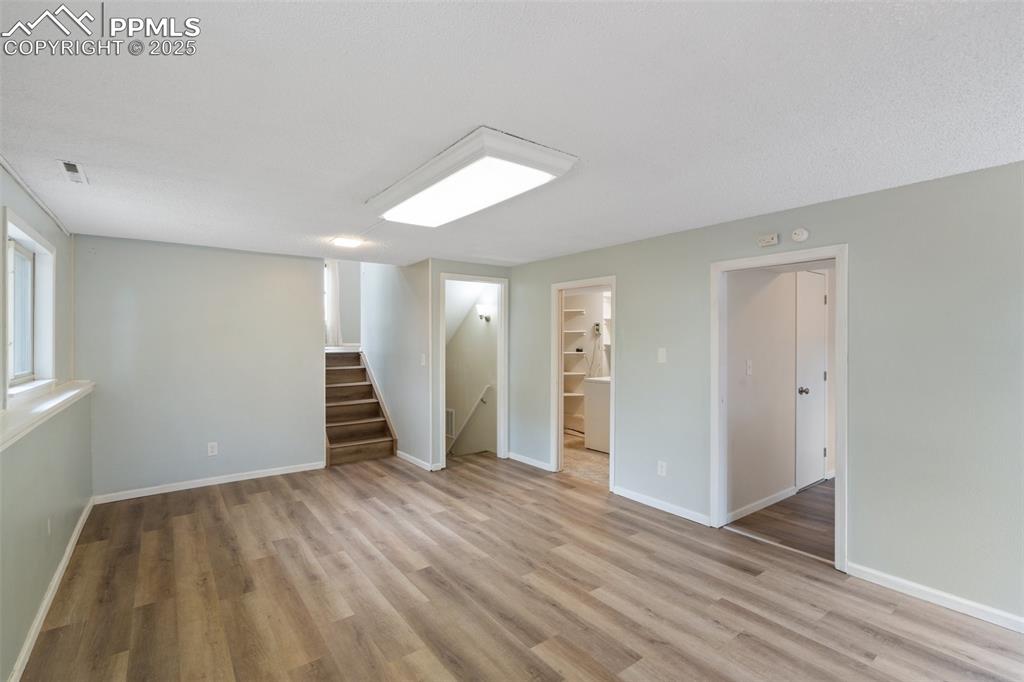 Image 17 of 25: Lower level Family Room with stairway and light wood finished floors