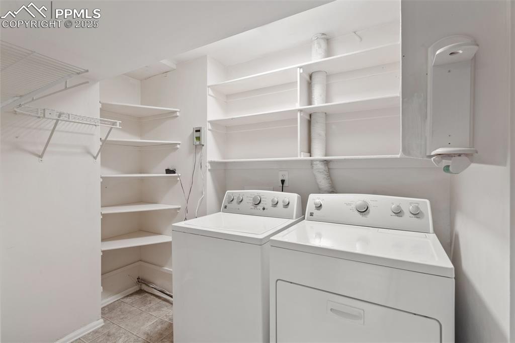 Image 21 of 25: Laundry room with washer and clothes dryer and light tile patterned floors