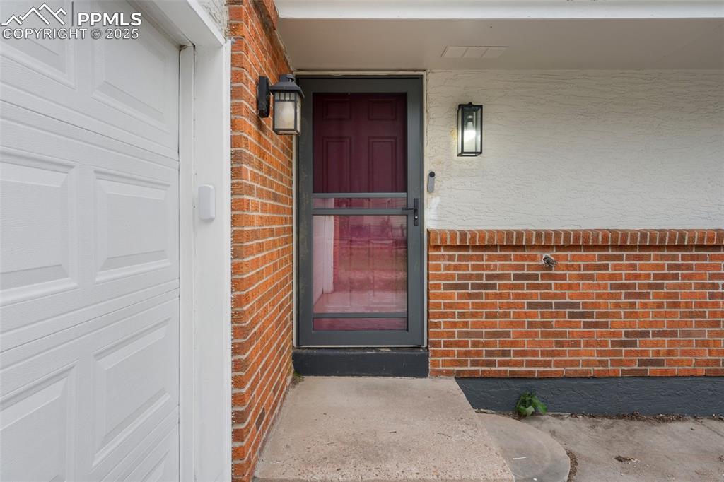 Image 4 of 25: Doorway to property featuring brick siding