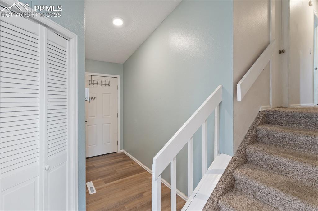 Image 6 of 25: Entry way with stairway featuring wood finished floors and a textured ceili