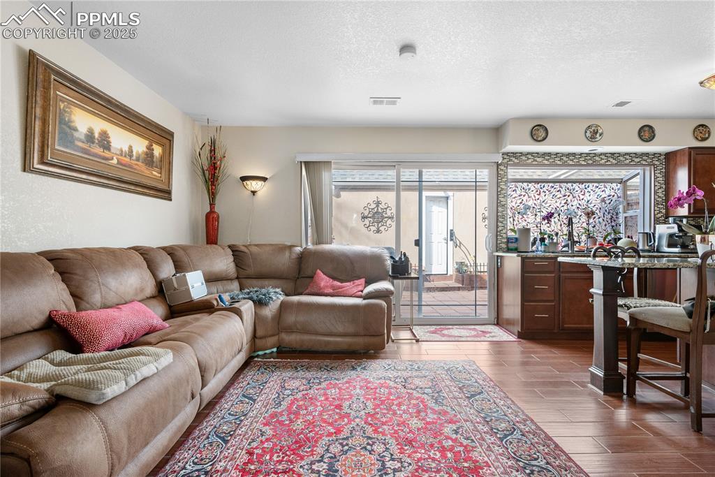 Image 23 of 38: Living room featuring a textured ceiling and dark wood-style flooring