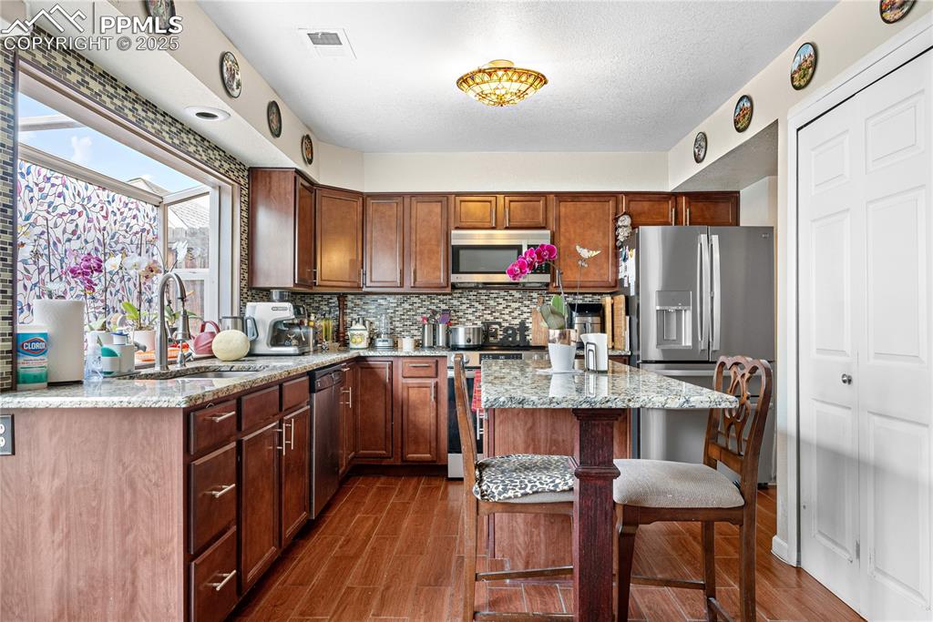 Image 29 of 38: Kitchen featuring stainless steel appliances, a breakfast bar, backsplash, 