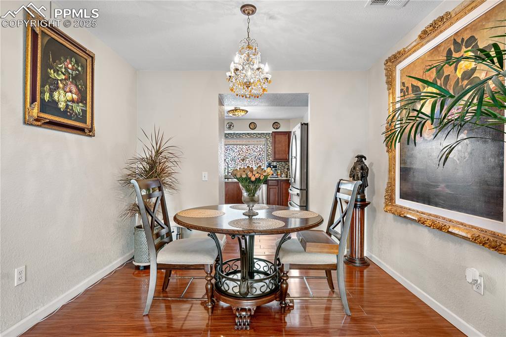 Image 30 of 38: Dining room with wood finished floors and a chandelier