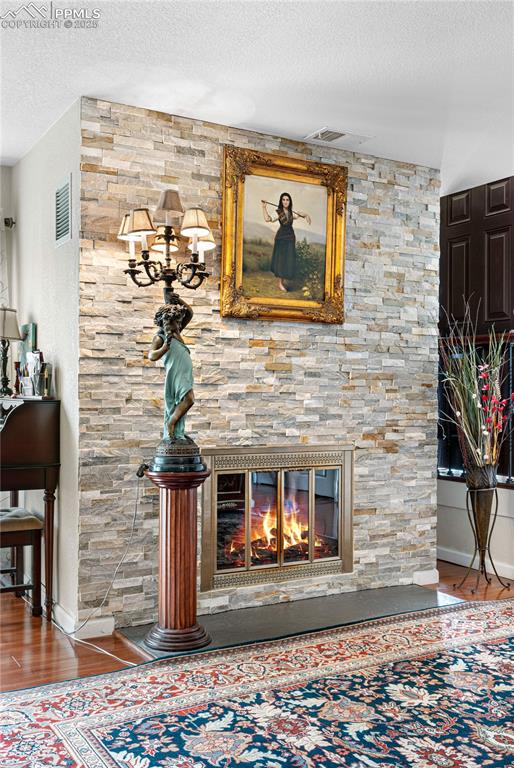 Image 31 of 38: Detailed view of a textured ceiling, a stone fireplace, and wood finished f