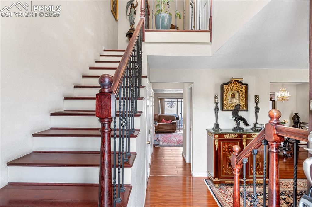 Image 35 of 38: Staircase with wood finished floors and a chandelier