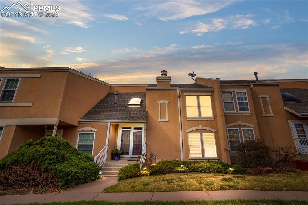 Image 38 of 38: View of front of house with stucco siding and a shingled roof