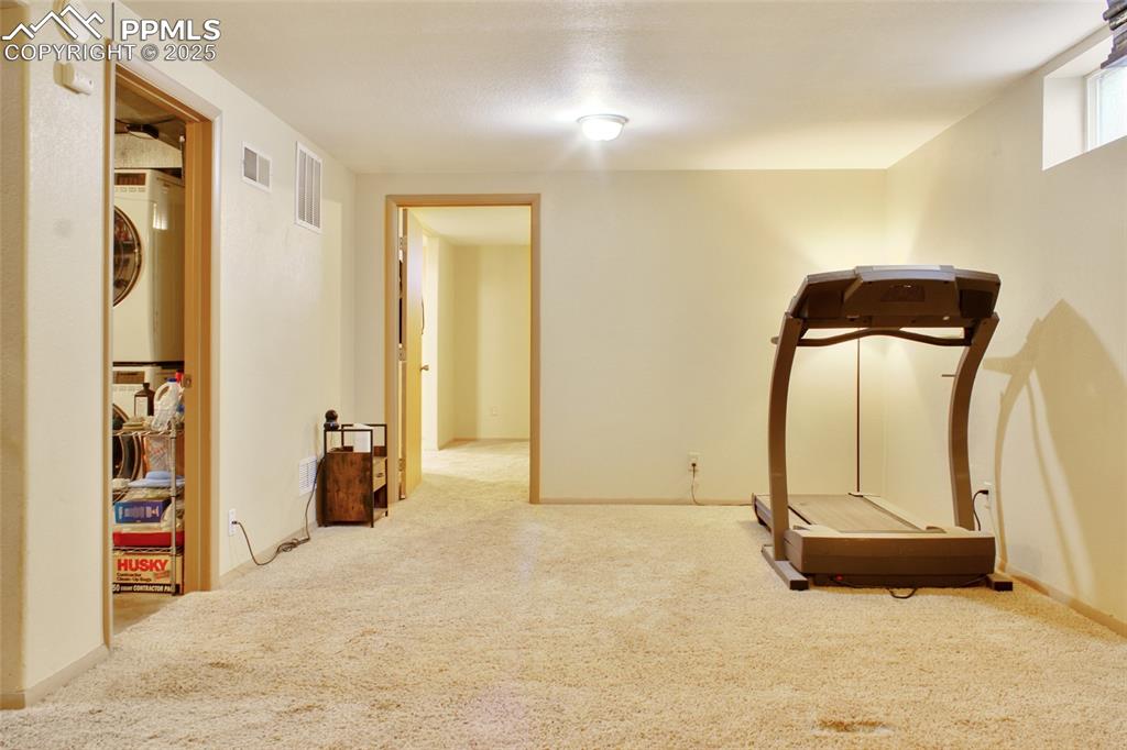 Image 19 of 28: Exercise area with carpet floors and estacked washer and dryer