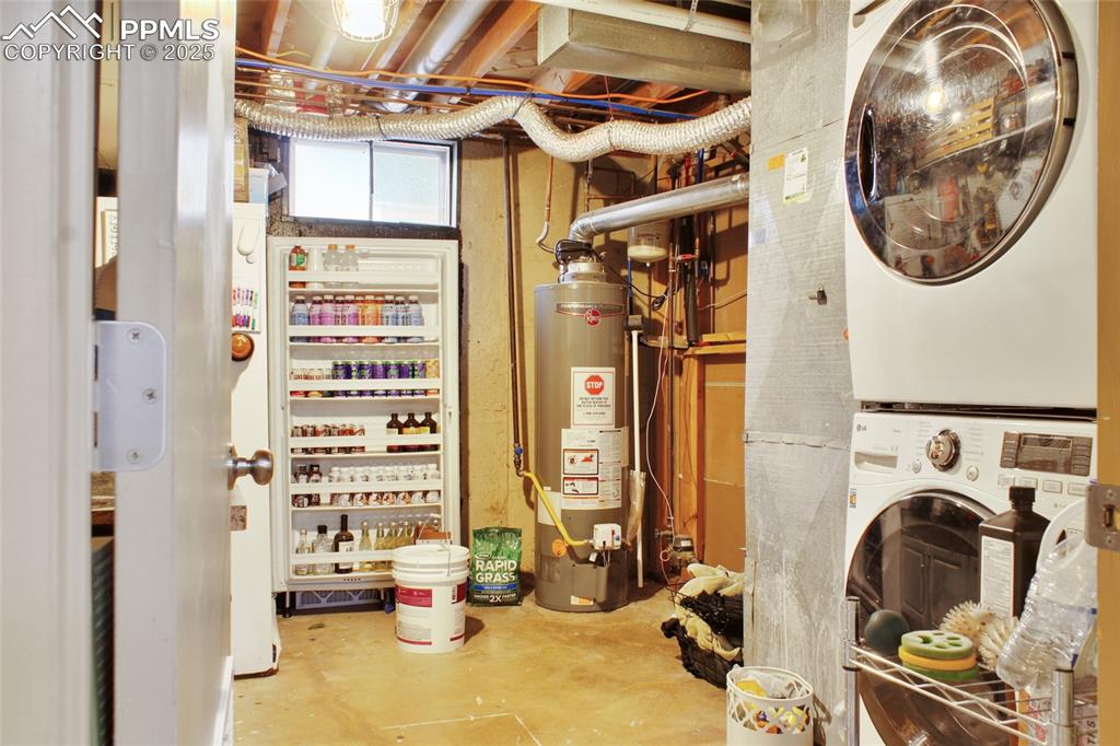 Image 20 of 28: Utility room with water heater and stacked washing machine and dryer