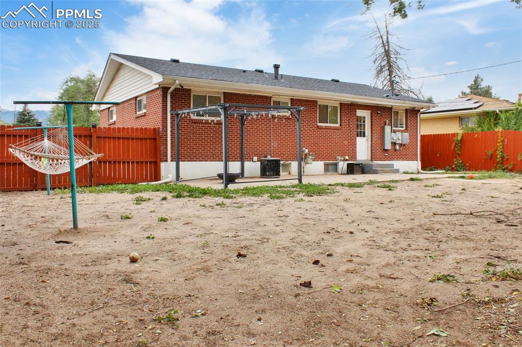 Image 21 of 28: Back of house with a patio, brick siding, and a fenced backyard