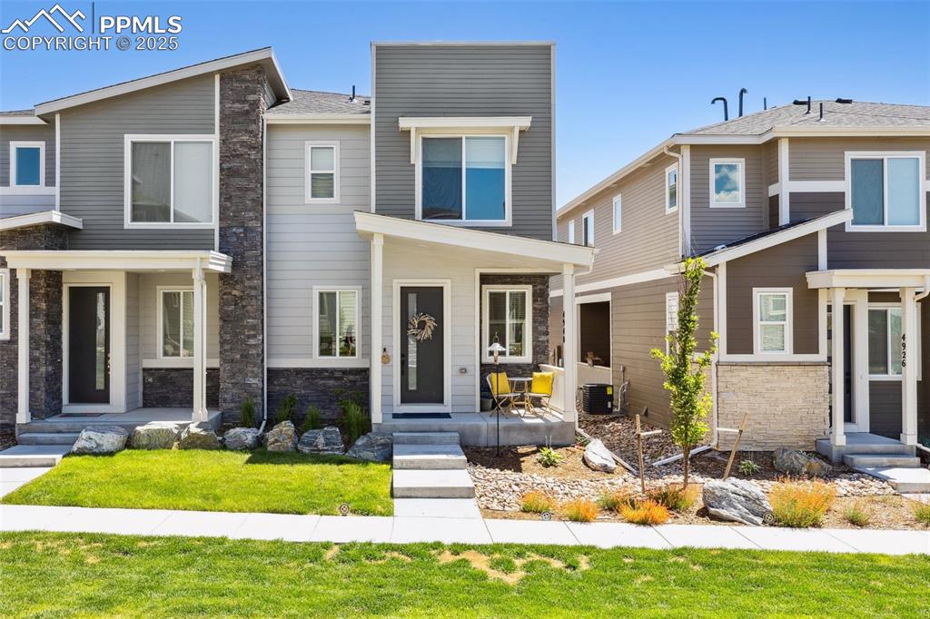 Caption: View of front of house featuring stone siding and a covered front porch