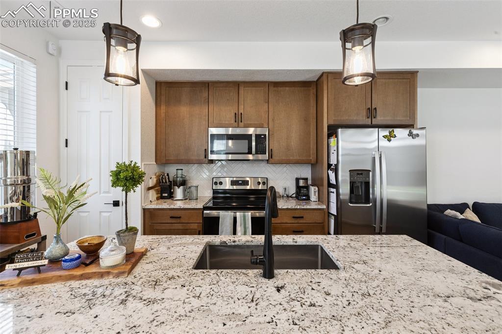 Image 12 of 46: Kitchen featuring stainless steel appliances, light back splash, maple cabi