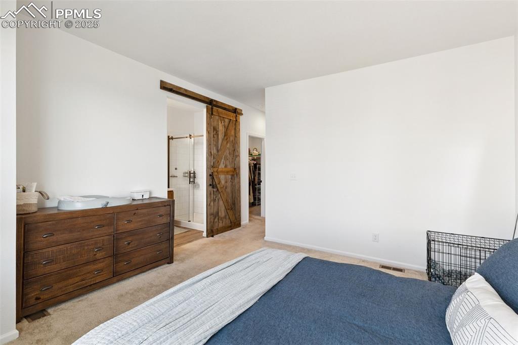Image 22 of 46: Bedroom featuring light colored carpet and a barn door to the adjoining bat