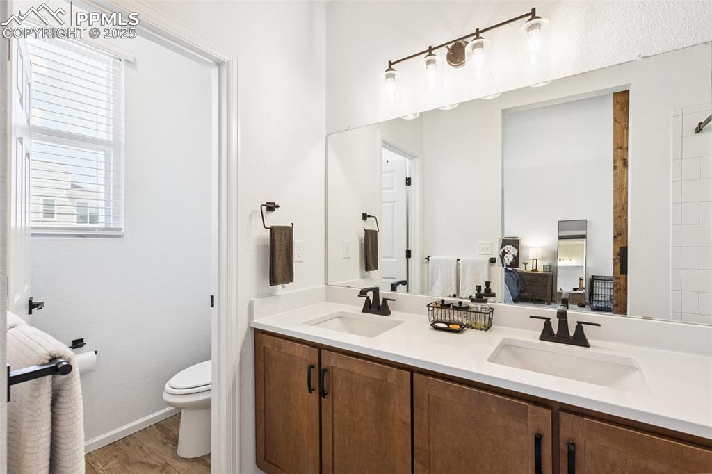 Image 23 of 46: View of the primary bathroom double vanity with quartz countertops and mapl