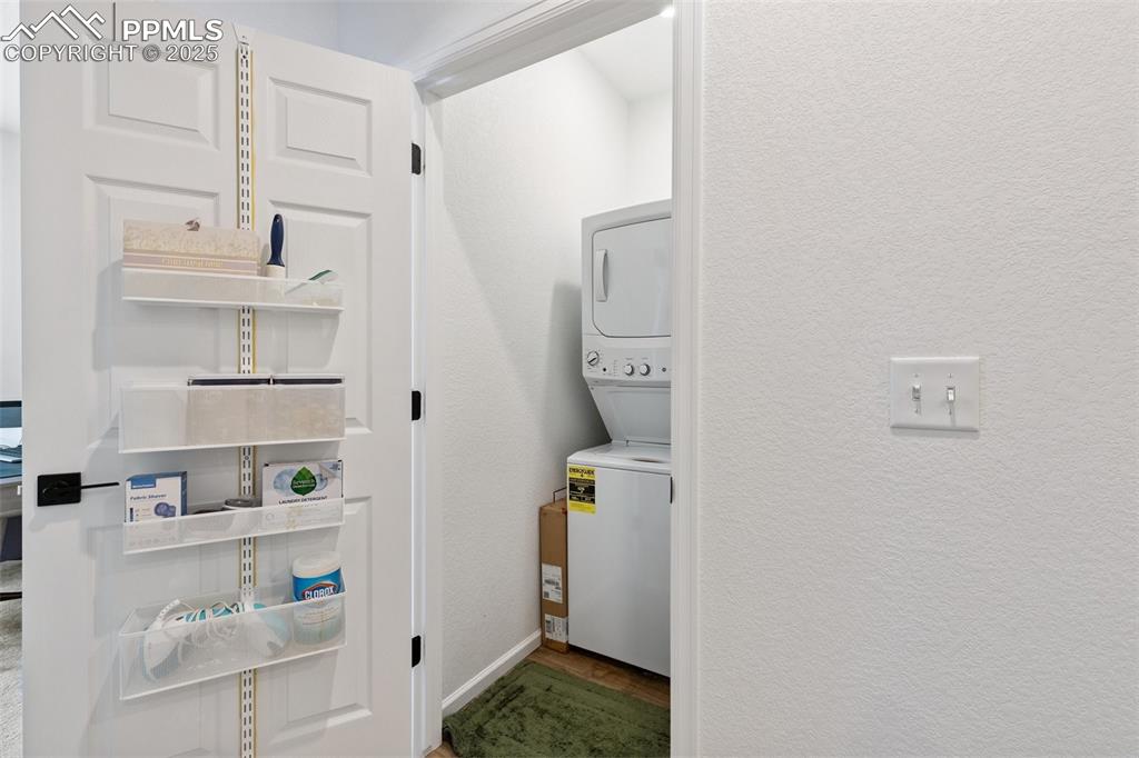 Image 32 of 46: Laundry area featuring stacked washing machine and dryer with built in shel