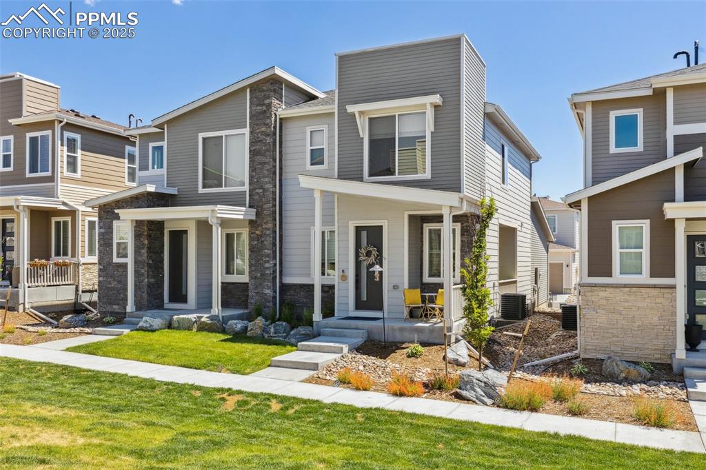 Image 4 of 46: View of front of house with stone siding and a covered patio