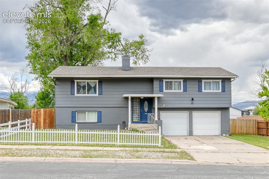 Image 1 of 46: Split-level residence featuring a gray exterior, white picket fence, and a 