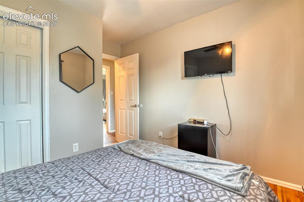 Image 23 of 46: Bedroom featuring light neutral wall paint, white trim, and wood-finish flo