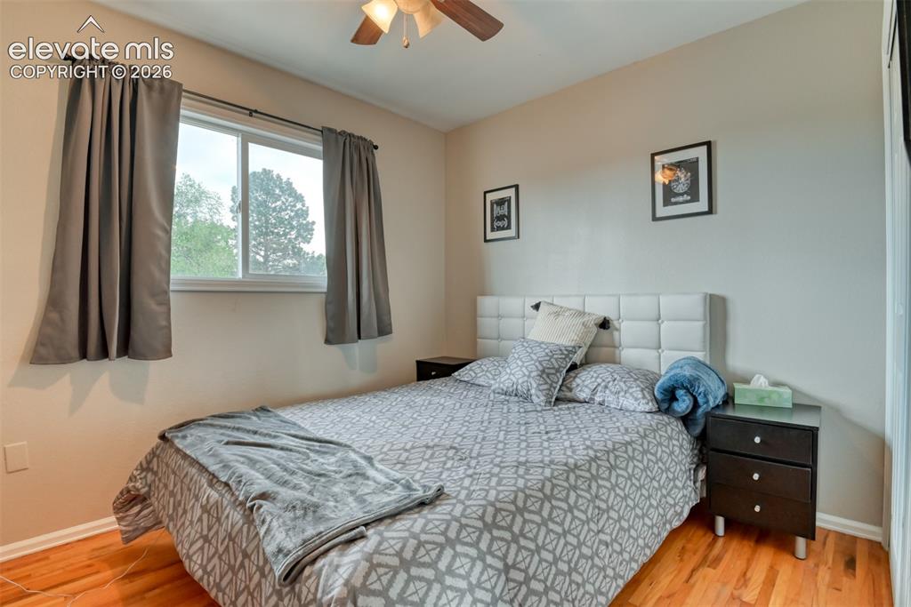 Image 25 of 46: Bedroom featuring wood-finish flooring, a double-paned window with curtain 